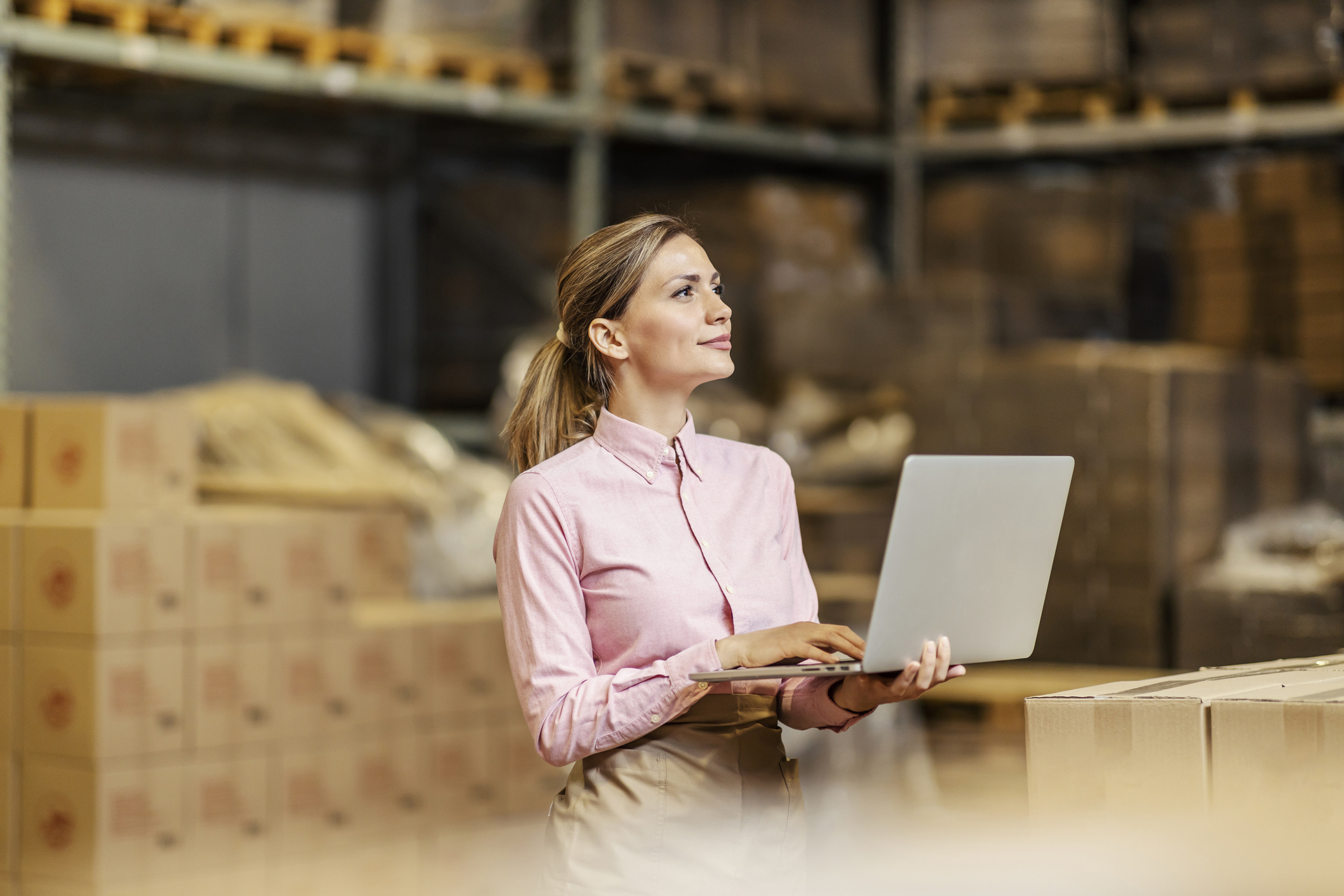 A food factory worker using laptop for checklist in the storage.