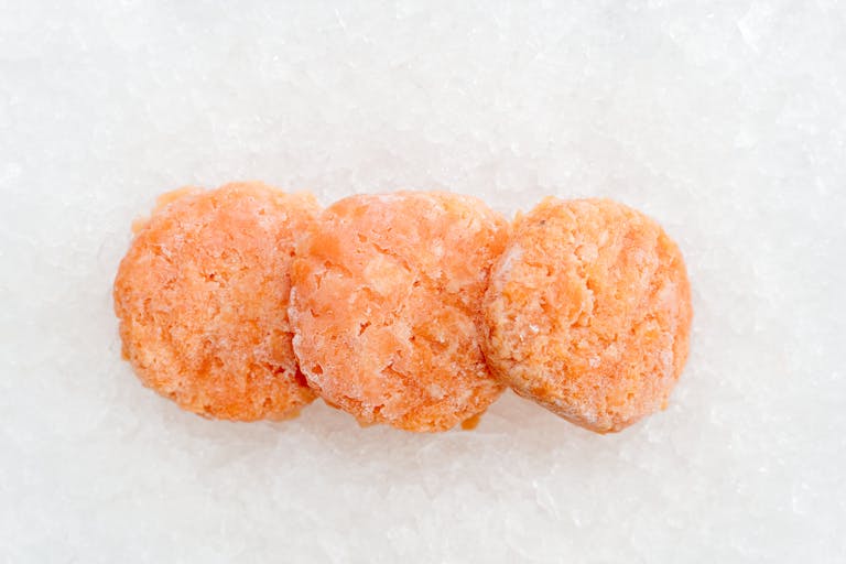 Three frozen salmon fillets on ice, top view with a cold and fresh appearance.