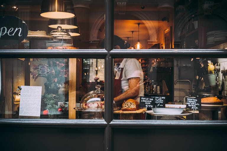 Warm bakery scene in London through window showcasing pastries and chef at work. Food Hygiene Level 2