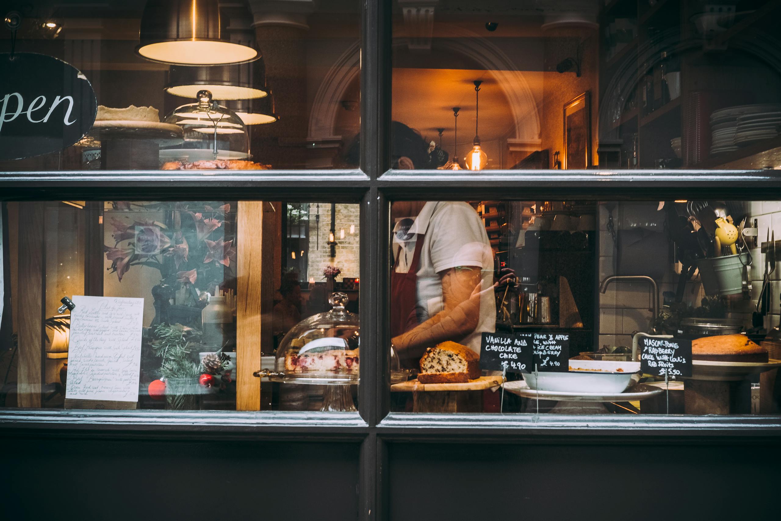Warm bakery scene in London through window showcasing pastries and chef at work. Food Hygiene Level 2